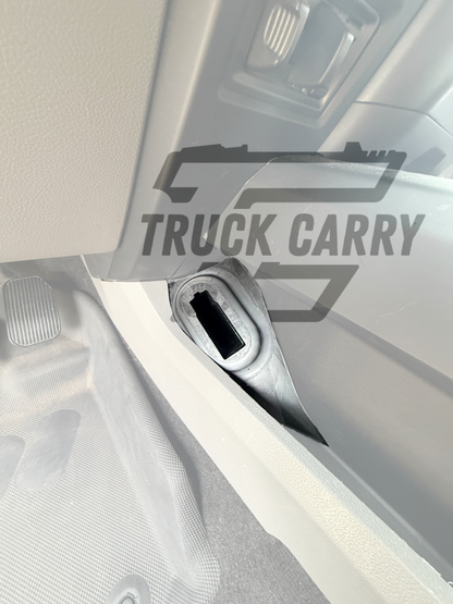 Close-up of a truck interior door panel with a hook-and-loop strap holding a gray rectangular accessory, overlaid with a semi-transparent 'TRUCK CARRY' logo.